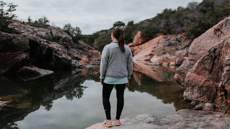 Lady looks out over a Texas lake: cabin rentals available for glamping vacations