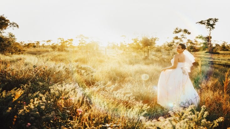 A bride in a field at a destination wedding location.