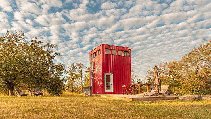 Red tiny house rental in a field in Canada.