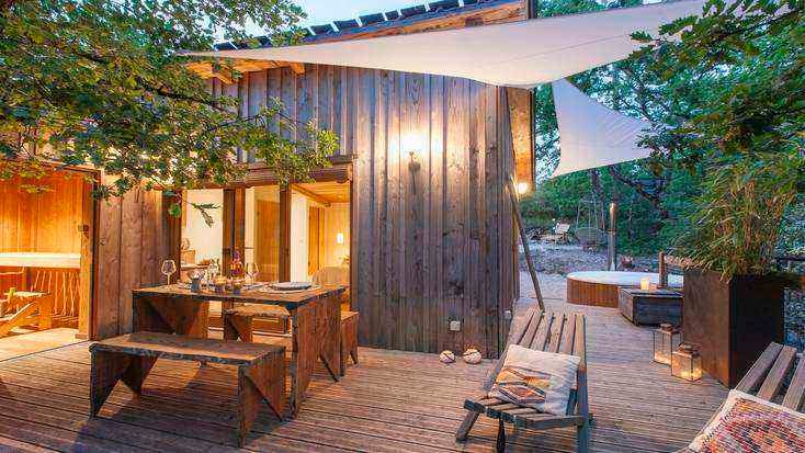 Private deck of a tree house in France with a picnic table and hot tub for where to travel in winter 2022.