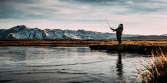 man fishing by lake after learning how to fish