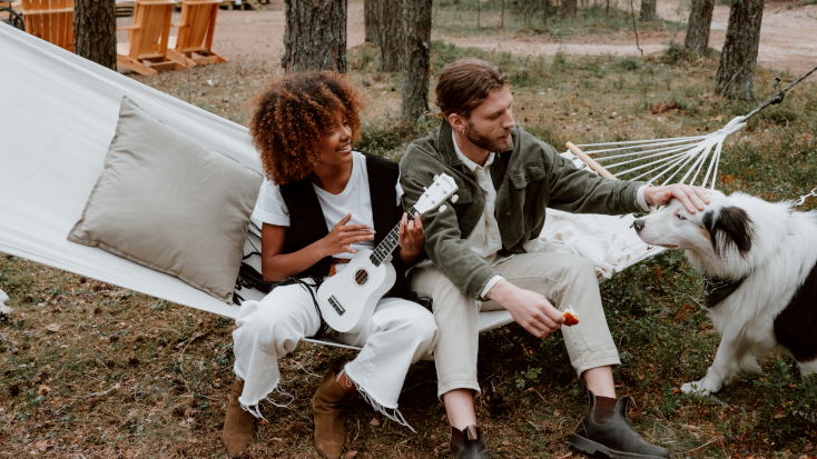 Glamping guest enjoying time outdoors in a hammock with their dog in a pet-friendly glamping tent. 