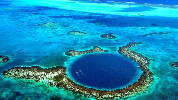 An aerial view of boats crossing the lagoon of the Belize Barrier Reef, accessible from of our best beaches, Placencia.