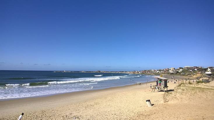 A view of a beach in Punta del Diablo, Uruguay, with a wide beach and a lifeguard's hut on the sand.