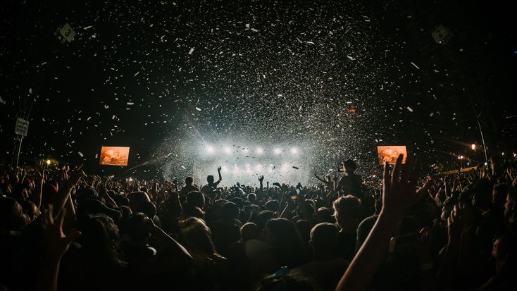 Australia Day being celebrated at Sydney Opera House with confetti, and people dancing in the crowd at concert. 
