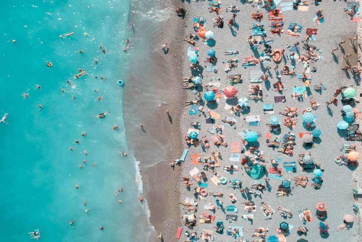 A aerial shot of a beach with people on the sand and in the water.