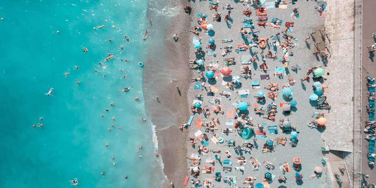 A aerial shot of a beach with people on the sand and in the water.