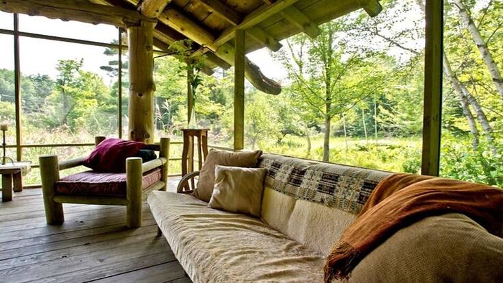 A covered porch surrounded by woodland 
