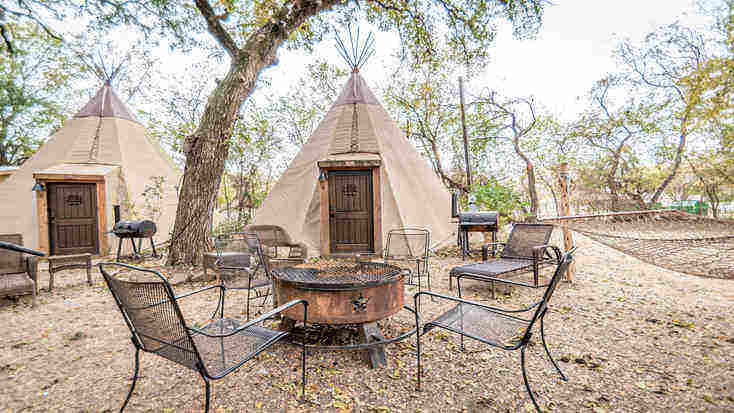 An outdoor seating area with a fire pit and barbecue in front of a tipi rental