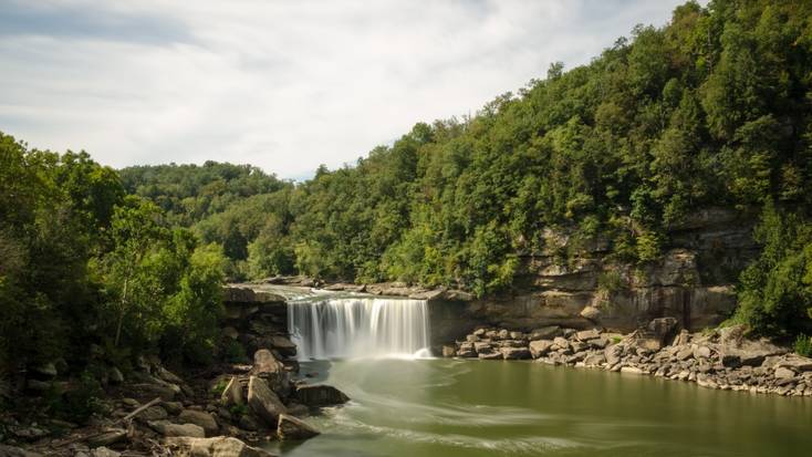A waterfall in the Cumberland Falls State Park surrounded by woodland