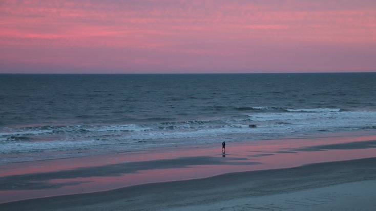 A person walking along Myrtle Beach at sunset