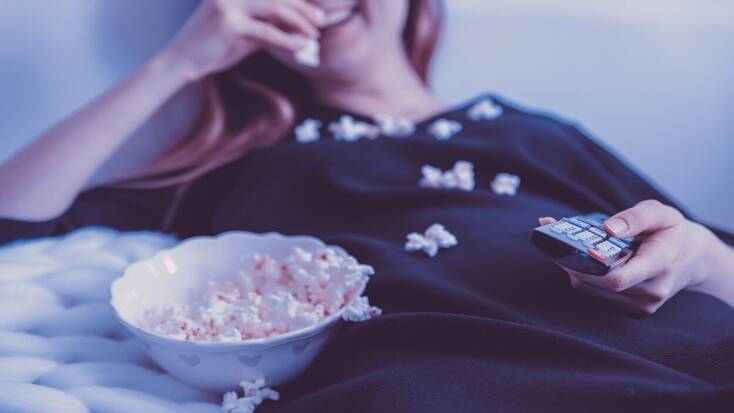A woman watching the best TV shows with some popcorn