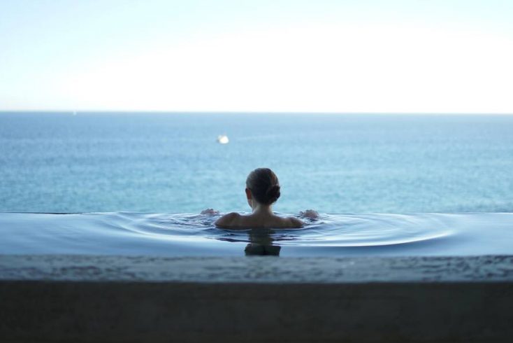 A woman in an infinity pool enjoying the best vacations in Mexico