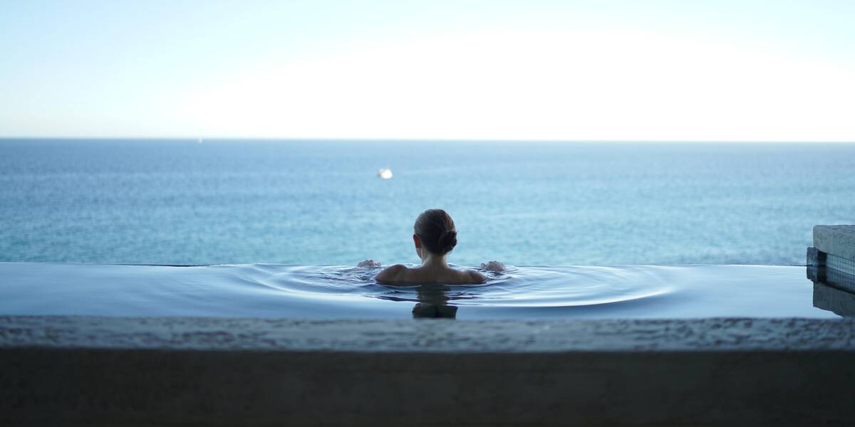 A woman in an infinity pool enjoying the best vacations in Mexico