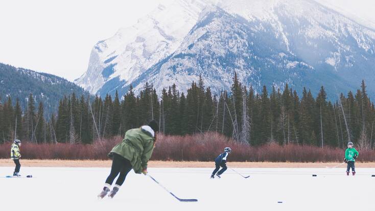 A family playing ice hockey on a frozen over lake in Canada in the winter