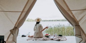 A traveler enjoying views of a lake from her glamping tent in secluded vacation spots