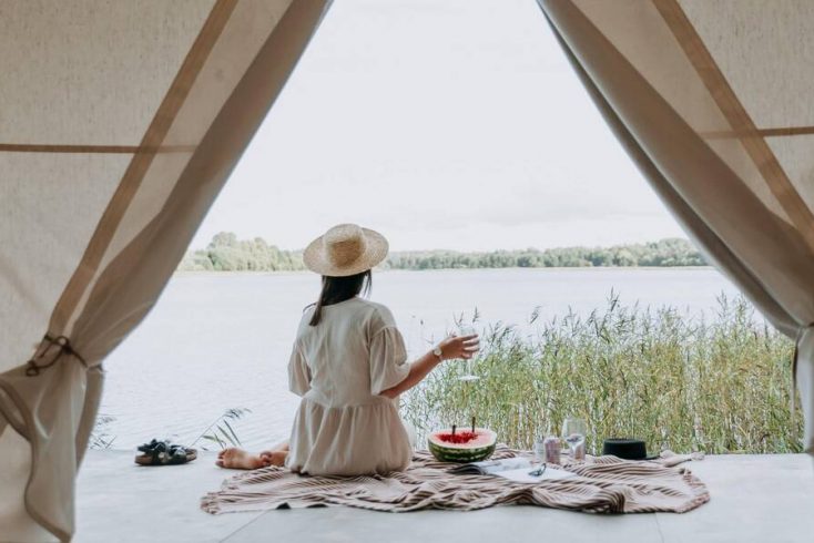 A traveler enjoying views of a lake from her glamping tent in secluded vacation spots