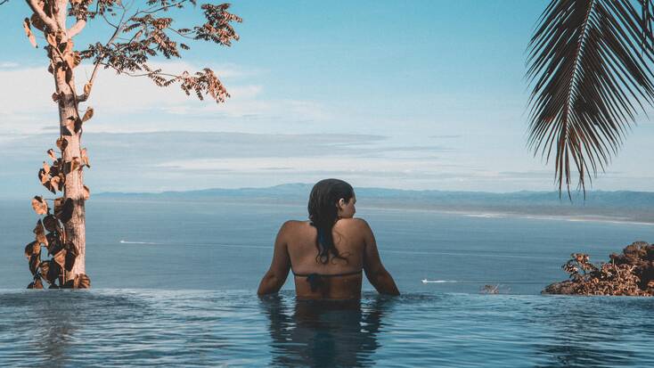 A woman in an infinity pool in her beachfront rental during luxury vacations