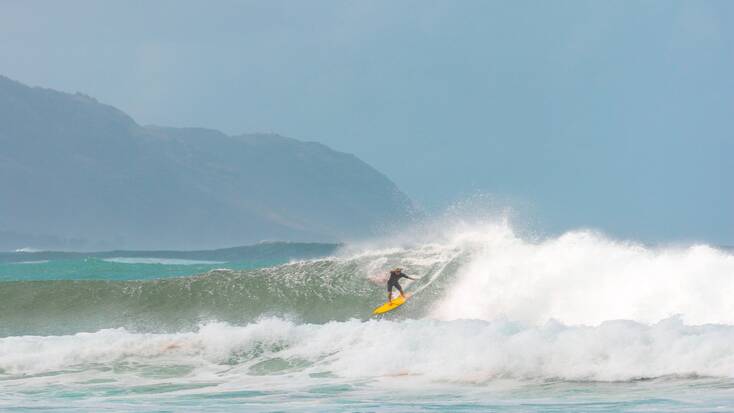 A traveler surfing a wave in Hawaii