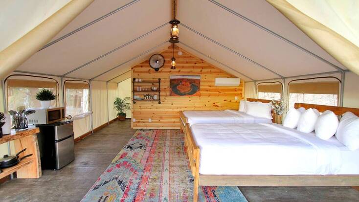 The interior of a stunning safari tent with 2 double beds and a kitchenette