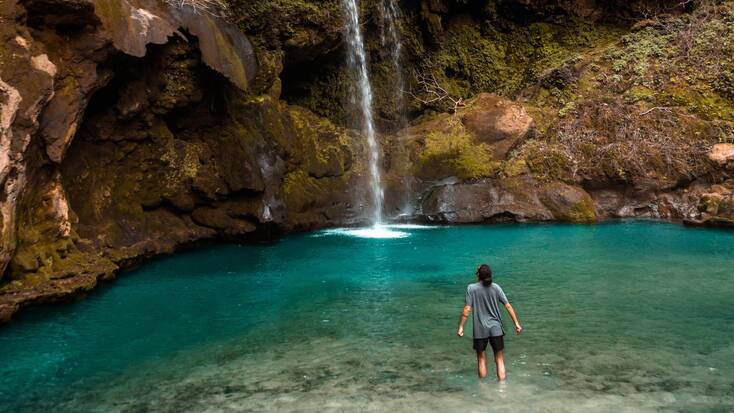 A traveler in a pool with a waterfall, enjoying one of the best spring break destinations