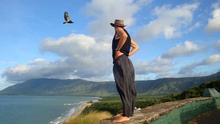 A tourist bird watching exotic birds fly over the ocean