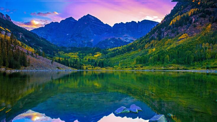 A stunning sunset over Colorado mountains behind a glistening lake