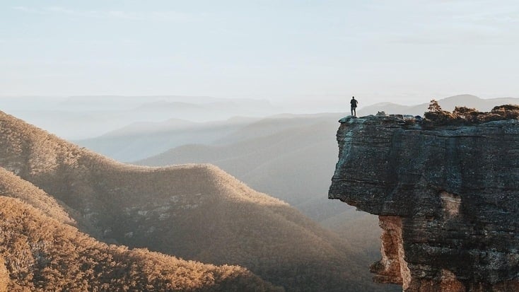 A man on top of a cliff overlooking Kanangra-Boyd National Park, NSW, for his Queen's Birthday Weekend getaways