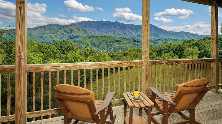View of the Great Smoky Mountains from private deck with deckchairs and yellow mug in Tennessee 