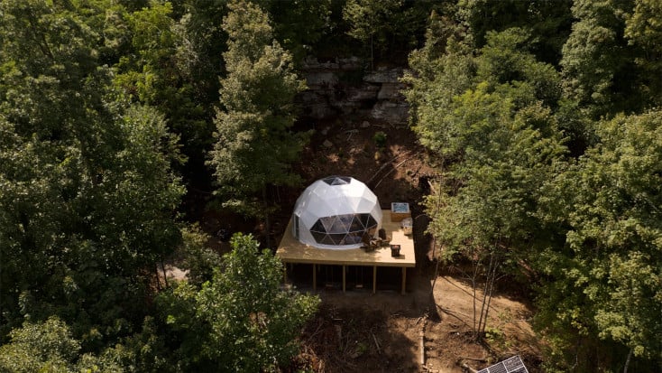 White geodesic dome on raised platform with hot tub surrounded by forest, TN