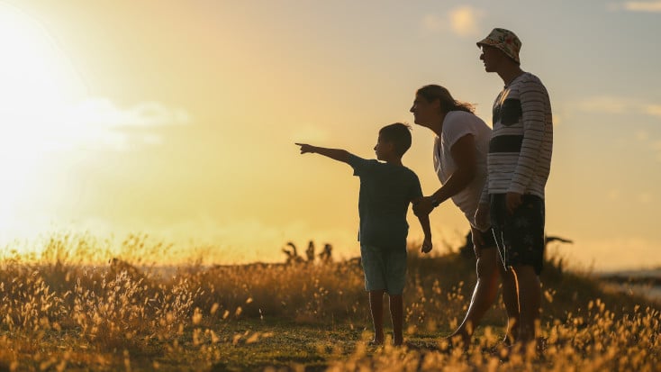 Family of three in a field pointing out the sunset, Virginia