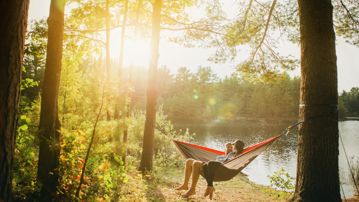Couple in a hammock by the river in a pine forest romantic getaway